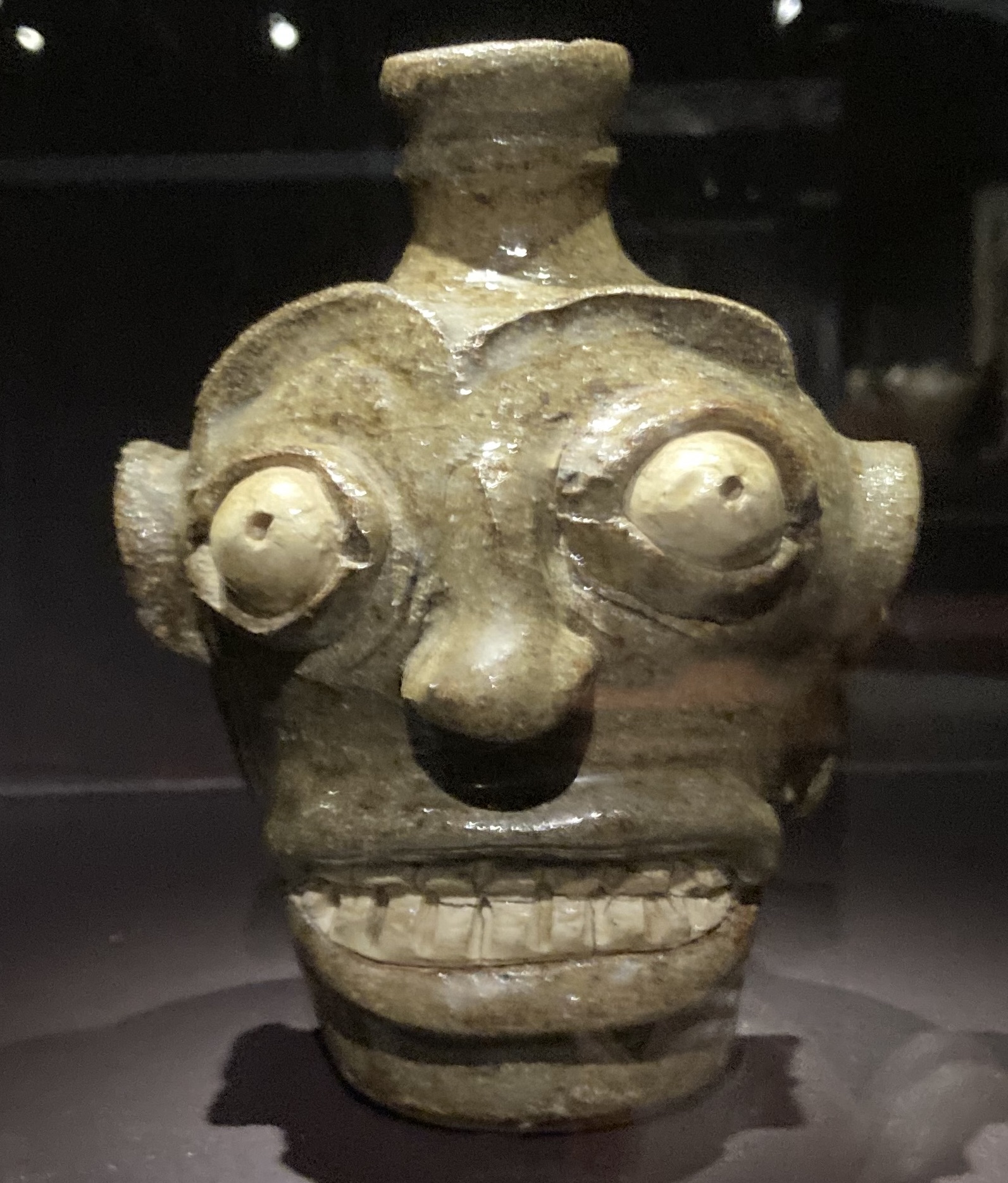 Face jug with protruding eyes and fierce set of teeth